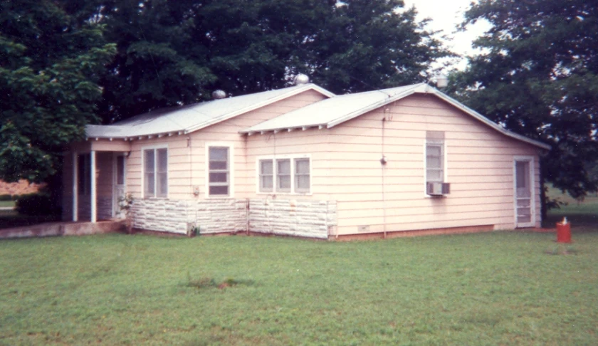 a small pink house sitting next to a tree