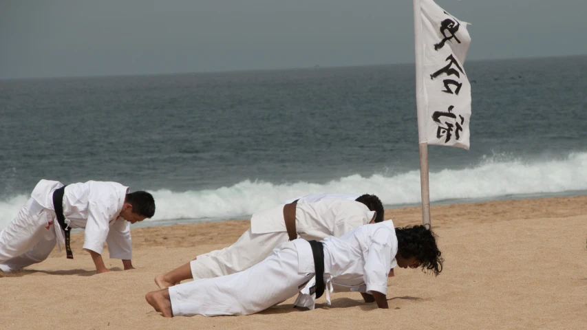 men in white clothes practicing martial at the beach