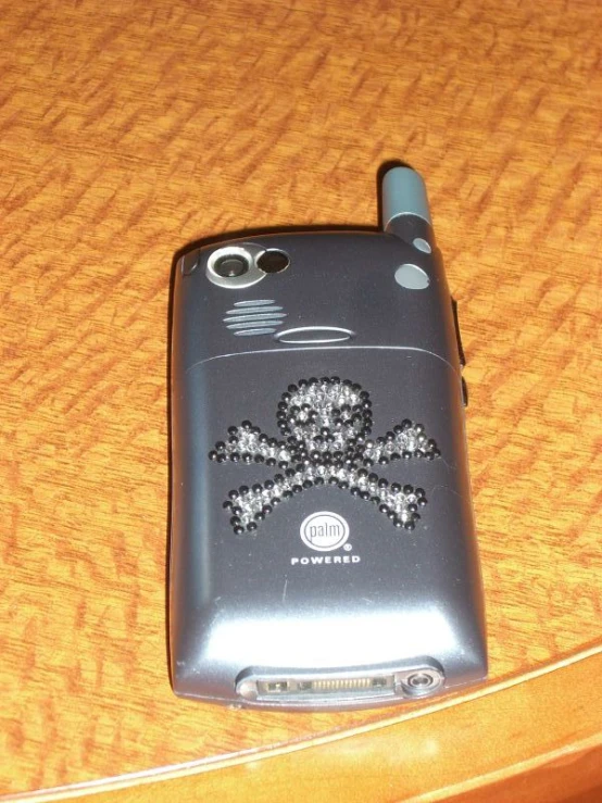 an old cell phone is decorated with skulls and bones