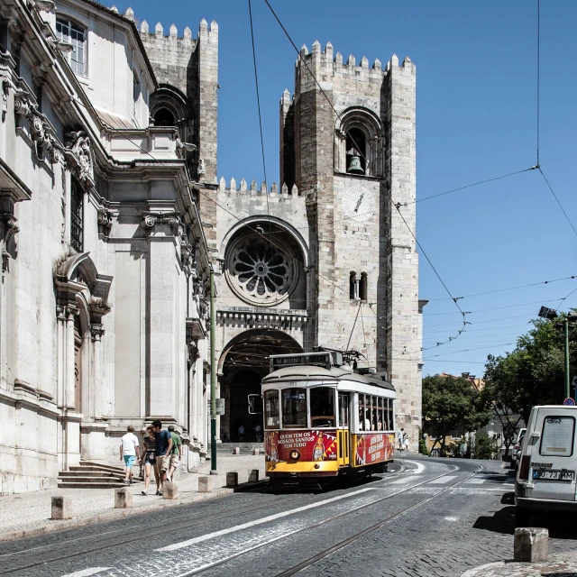 a yellow and red trolly passing by large old buildings