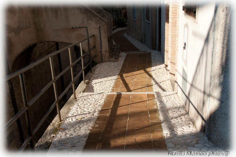 a narrow alleyway with some doors and railing