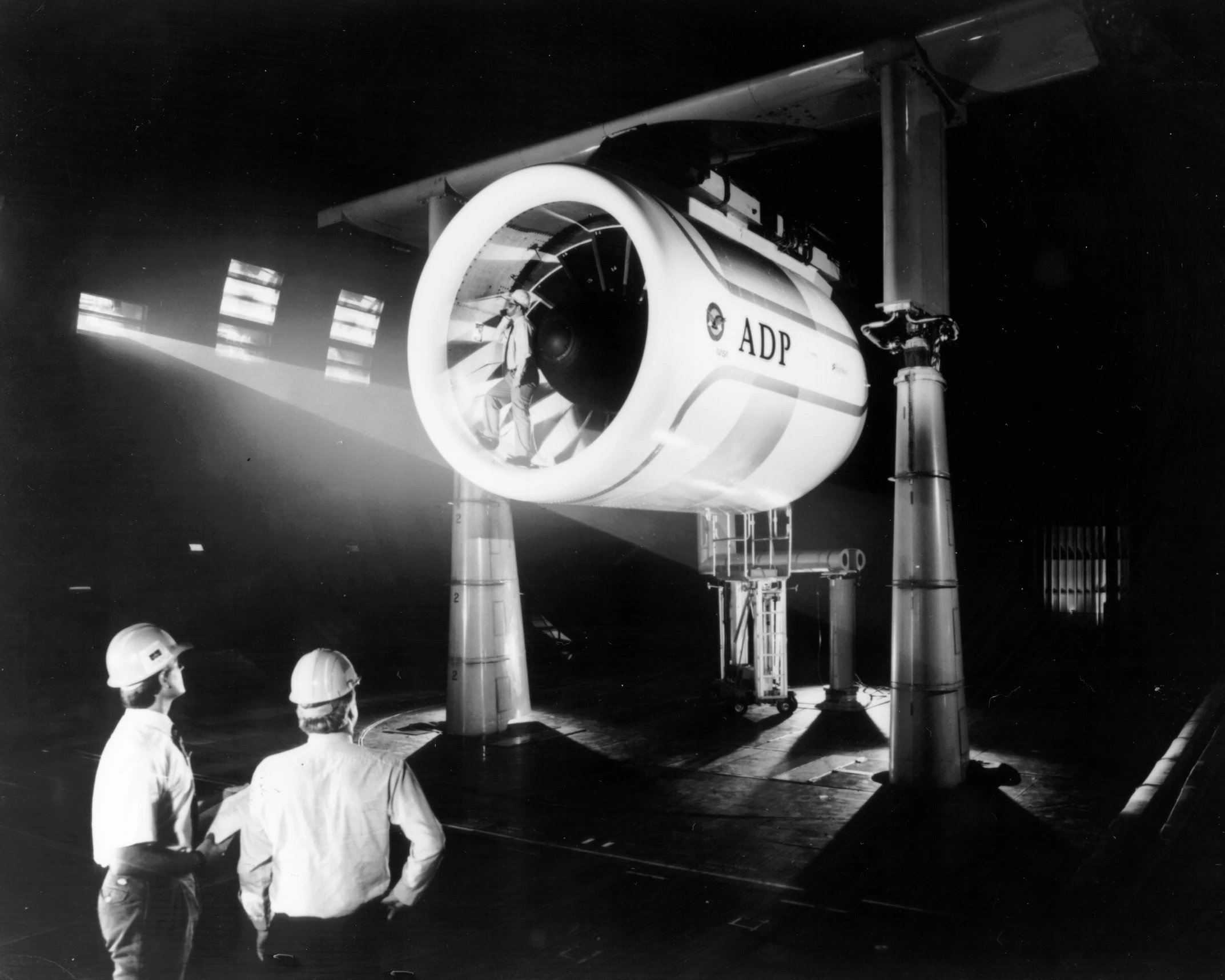 two men are looking at a large object on a building