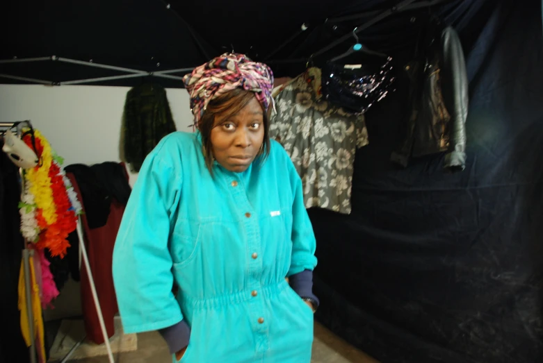 a woman that is standing in front of a lot of clothing