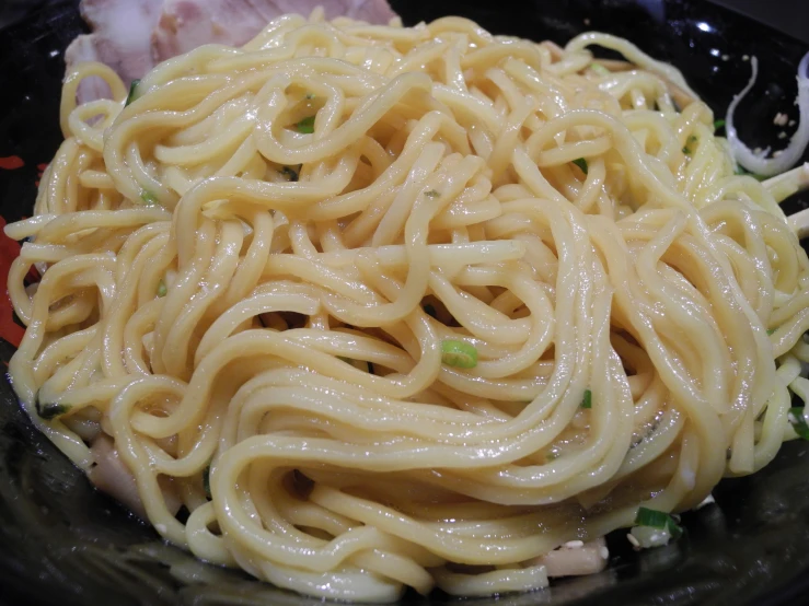 a black bowl filled with noodles and sauce