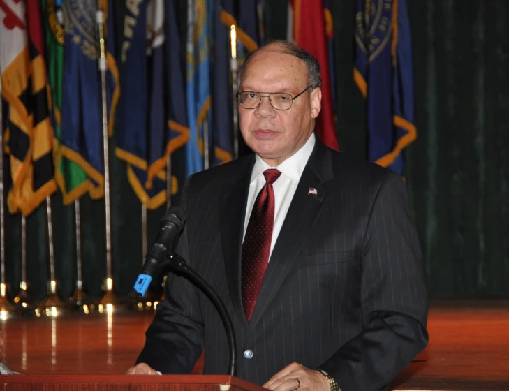 a man in a suit standing at a podium speaking