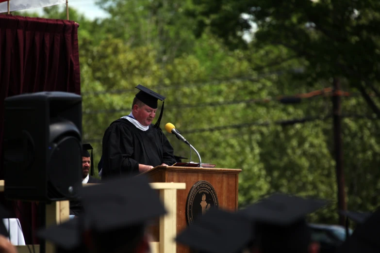 a man is standing at a podium at commencement
