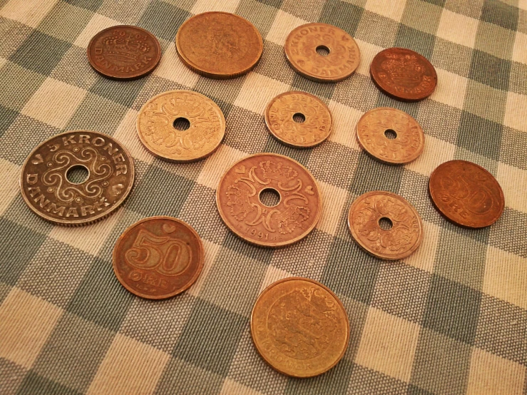 some brown and white foreign coins laying on a checkered cloth