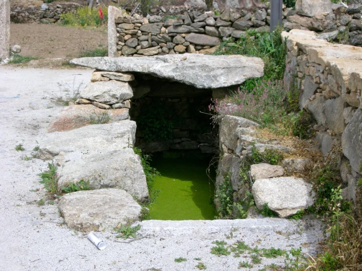 a pool of water in a stone tunnel next to a sign