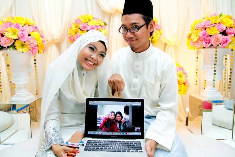 two people posing for a picture with a laptop