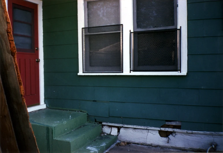 a green and red house with red doors