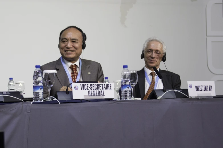 two men sitting in front of a blue table at a convention