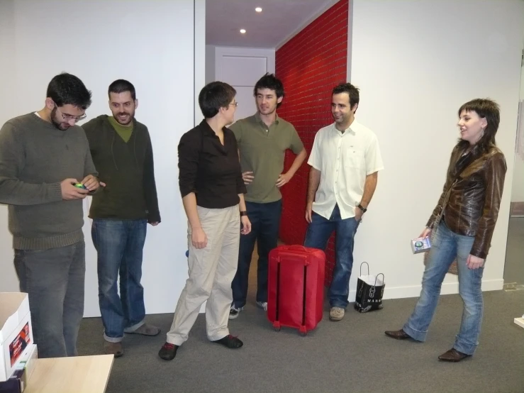 a group of people standing around and one person holding a red piece of luggage