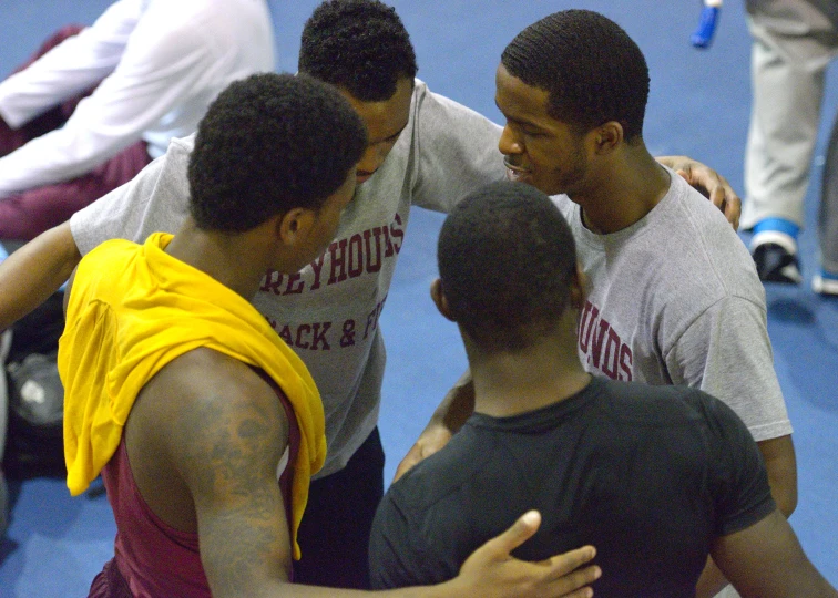 a group of men standing around a blue court