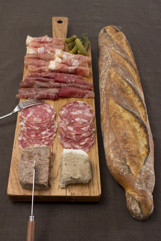 several foods laid out on a board next to a loaf of bread