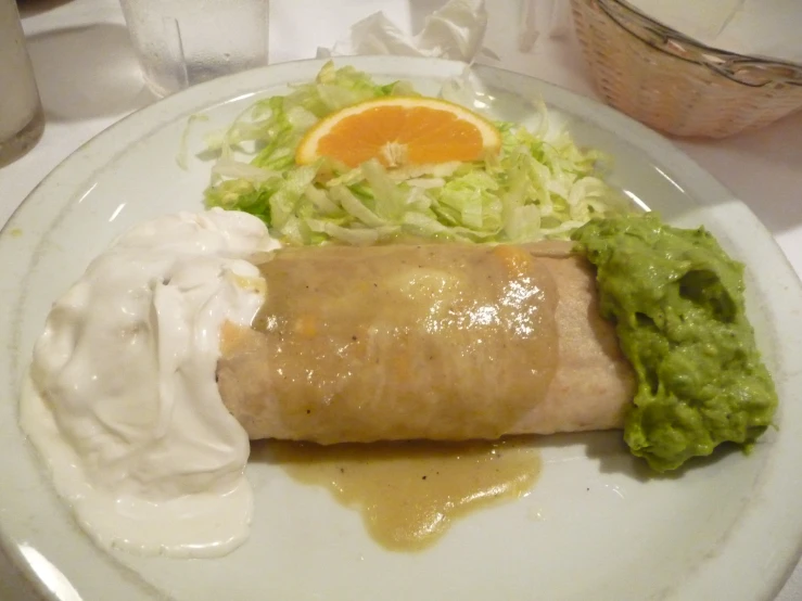 a burrito is on a plate with guacamole and sauce