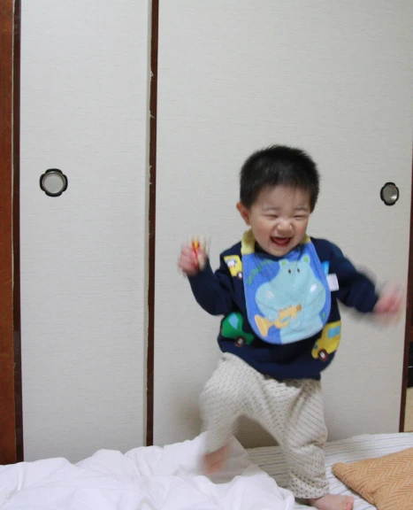 a toddler with his pajamas on jumping on a bed