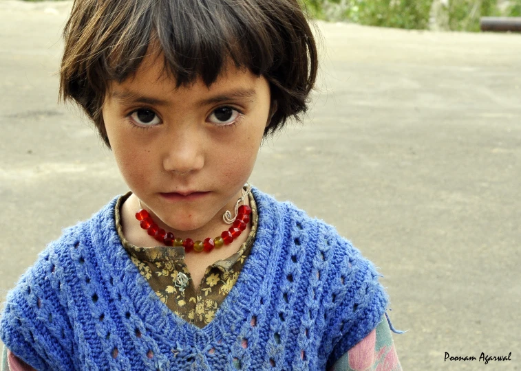  wearing a blue sweater and a red necklace