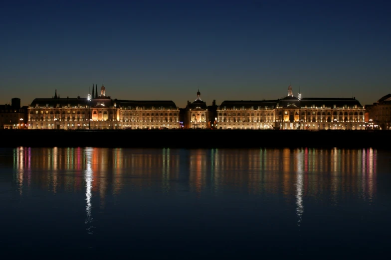 the buildings are along the river shore at night