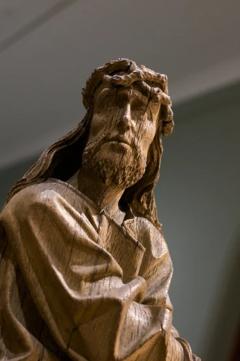 a statue of jesus holding his head up to his chest
