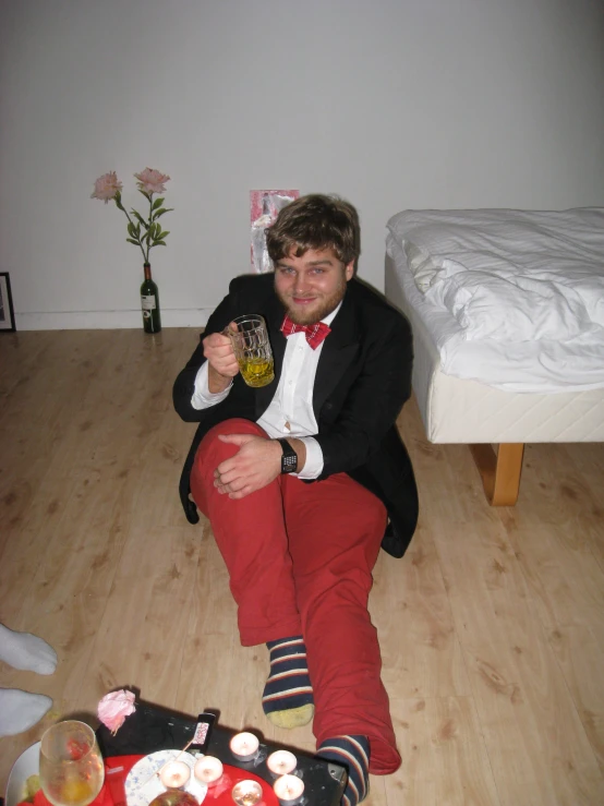 a man sits on the floor in red pants and a black jacket