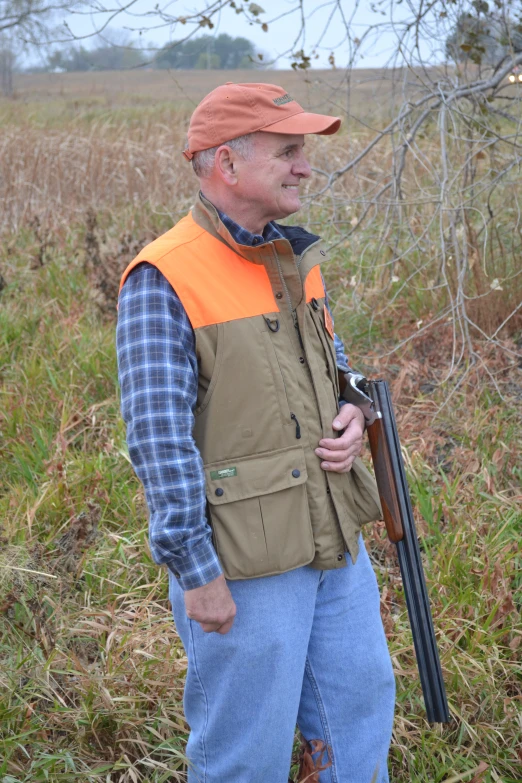 a man standing in a field holding a rifle