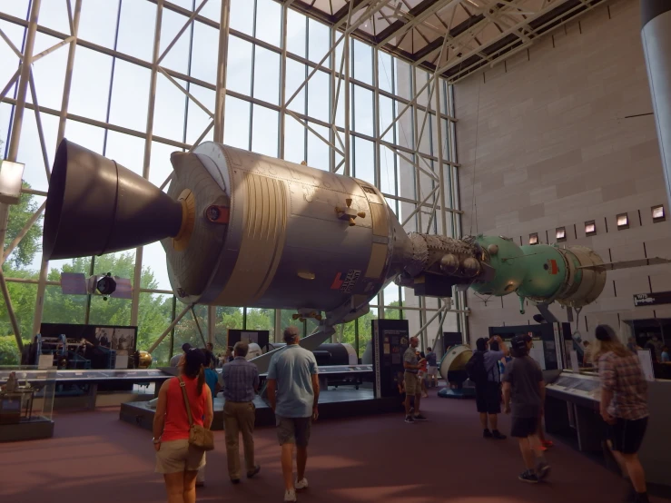 people inside a large building with an airplane like object on display