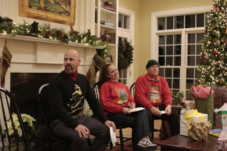 four people sitting in chairs, one with a present
