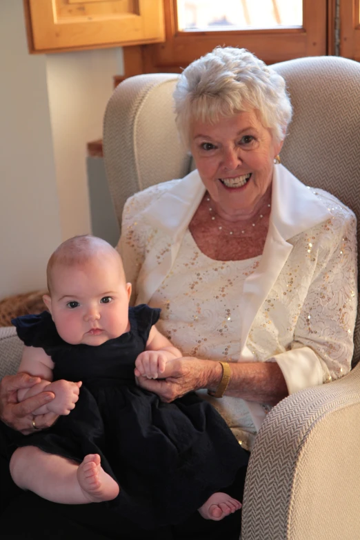 a woman sits in a chair holding a baby