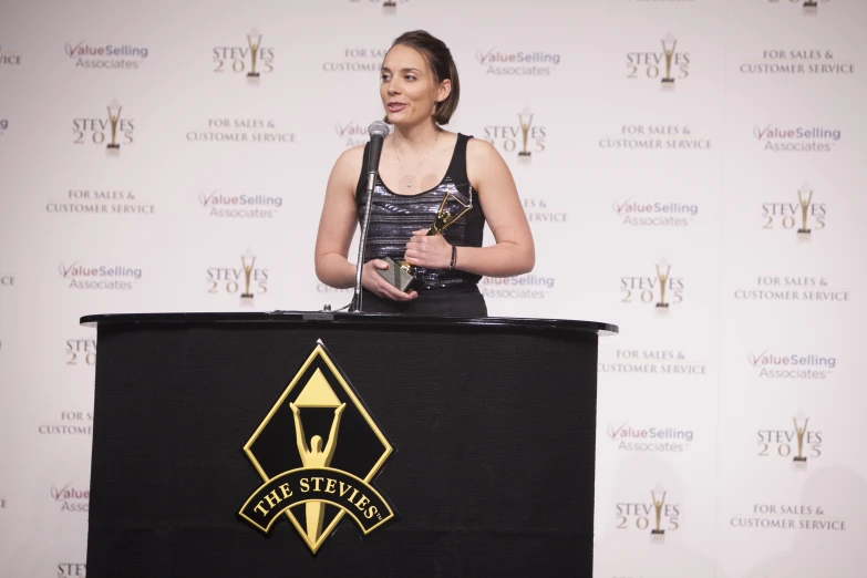 a woman standing on top of a stage holding an award