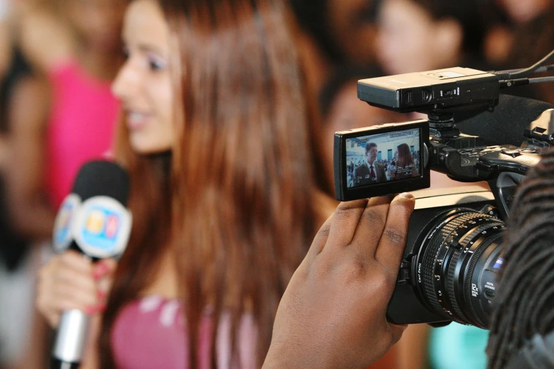 a camera and television set being held up by a woman