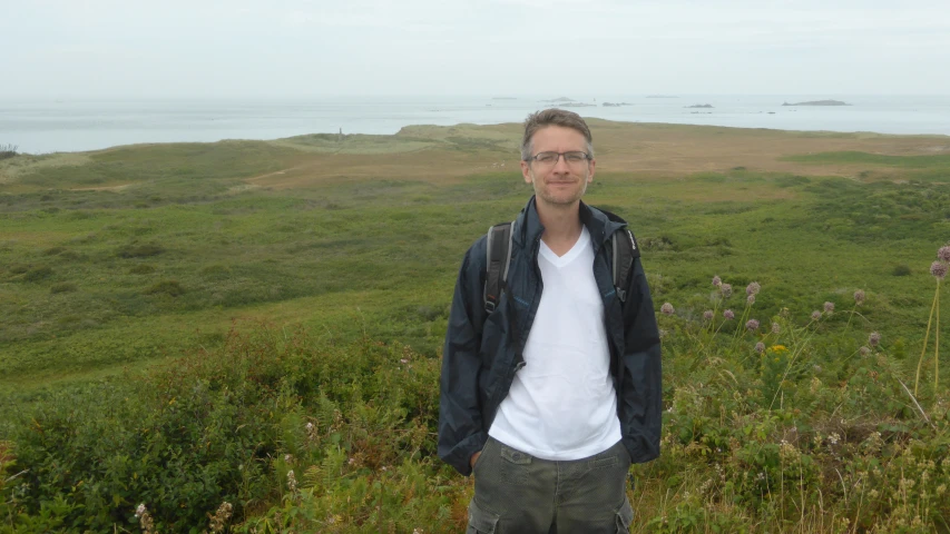 a man standing on the side of a grassy hill