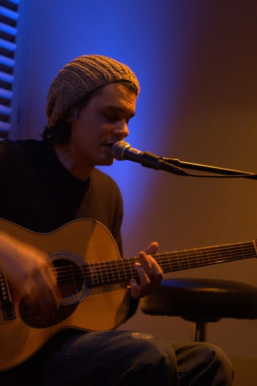 a young man playing a guitar and singing into a microphone