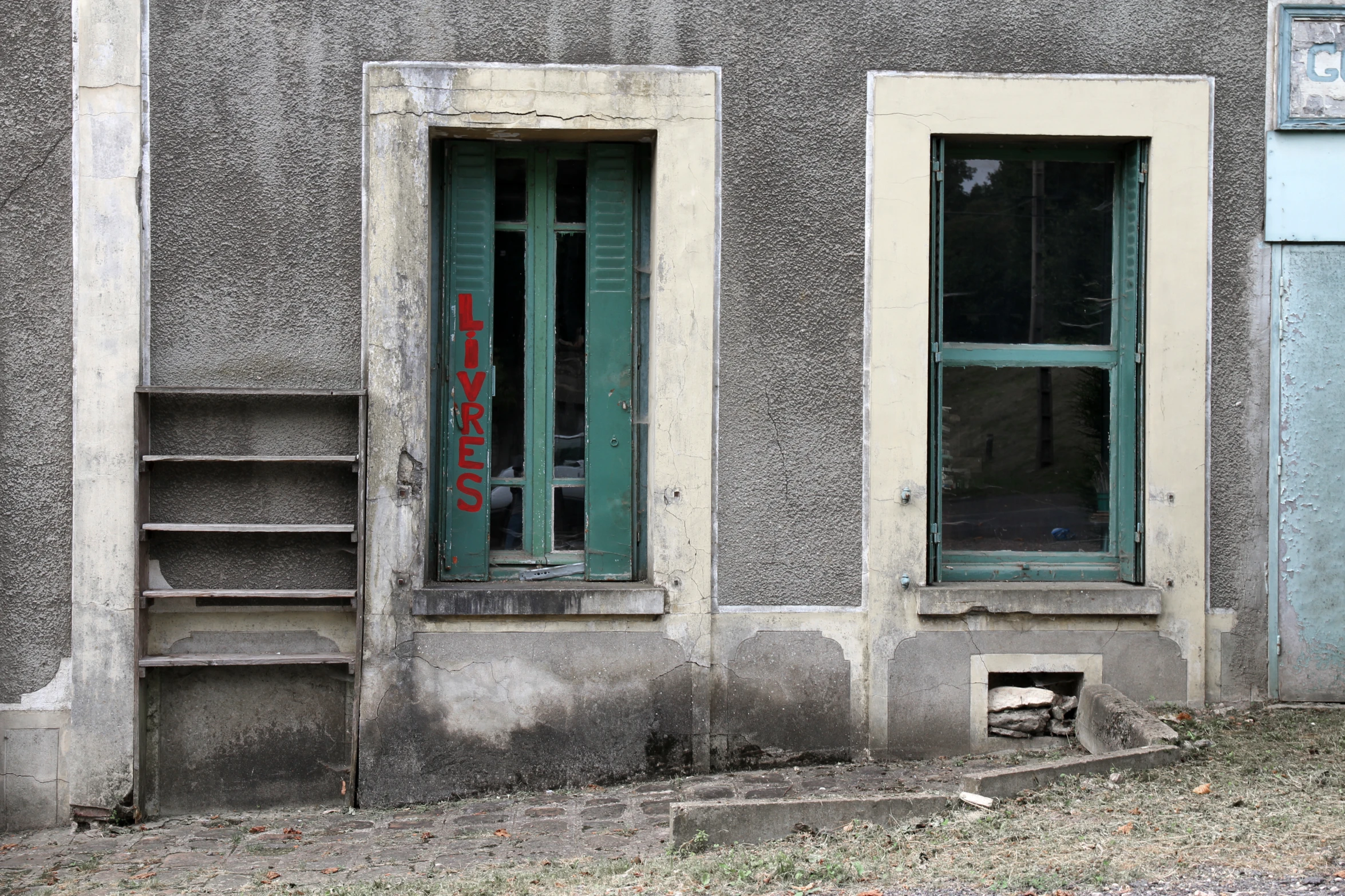 a concrete building with two windows and some steps on the side of the wall