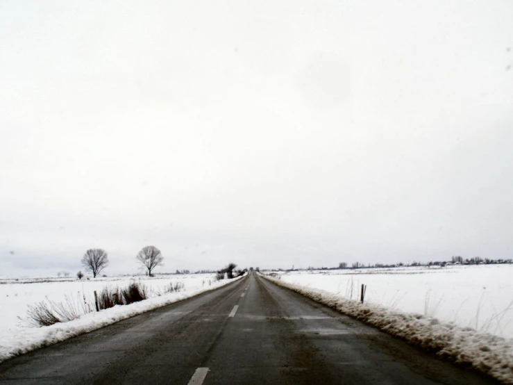 snow covered roadway with no cars driving down it