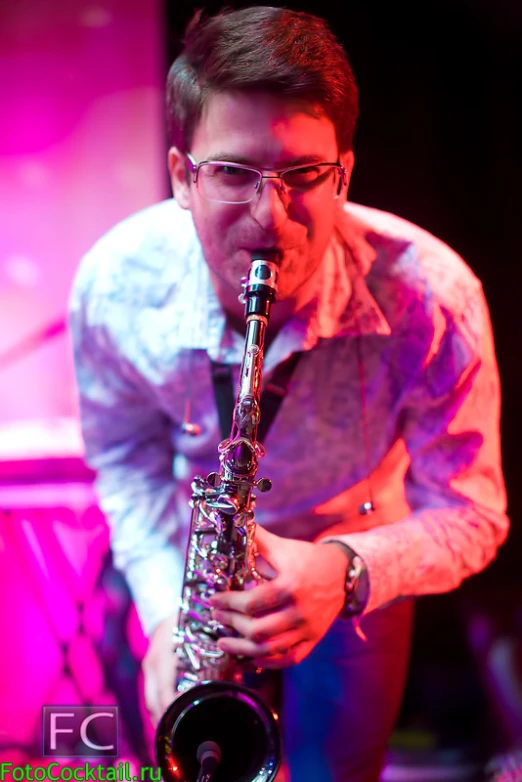 a man wearing glasses holding a saxophone in his hand