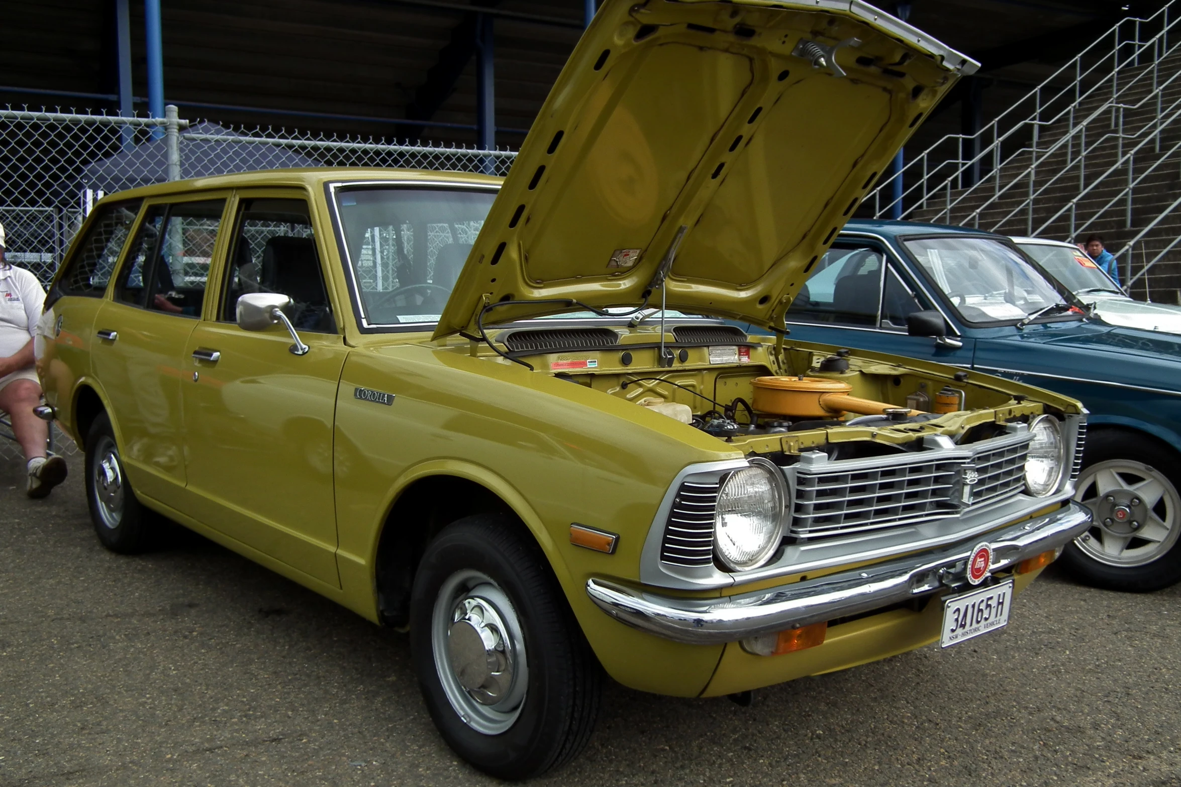 old model dodge sitting in a parking lot while a woman inspects it