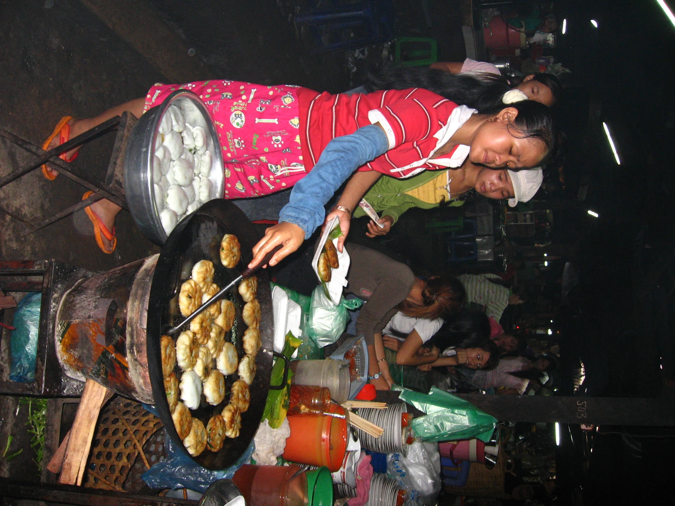 two women at an open market cooking food