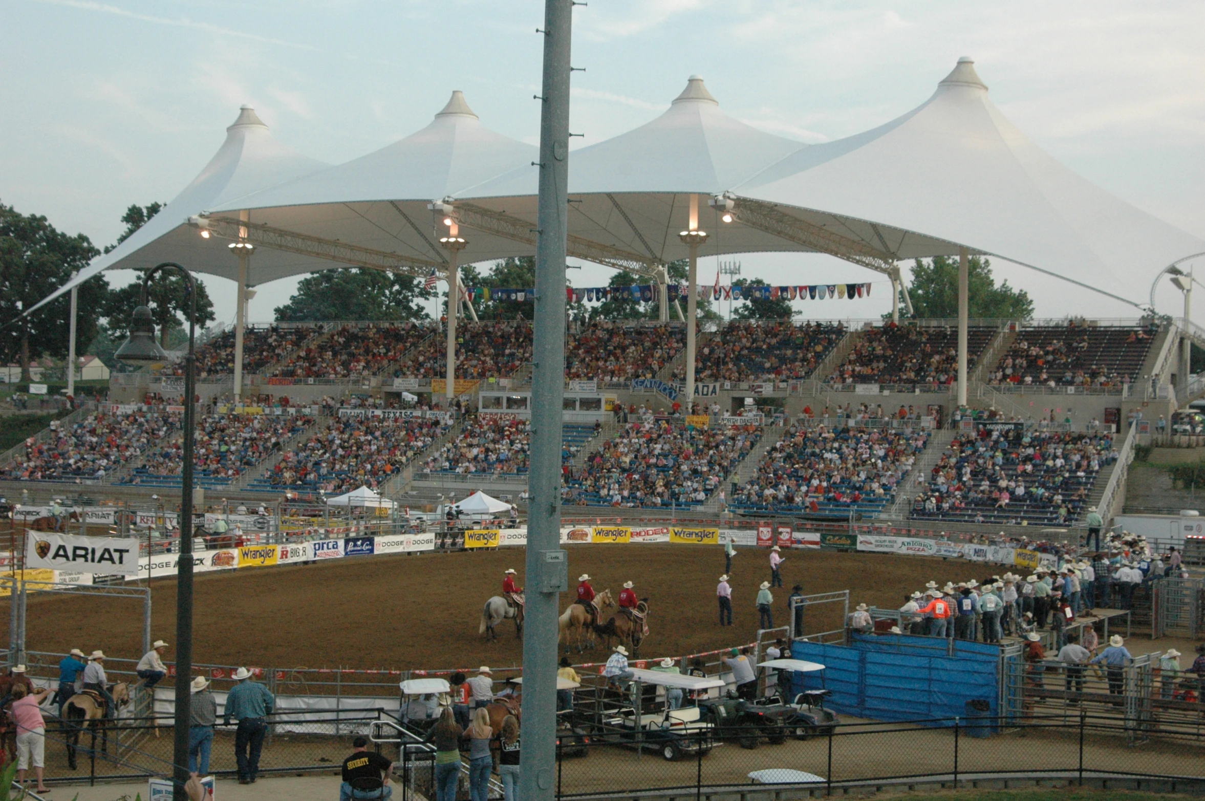 a crowd at a dirt arena for horseback racing