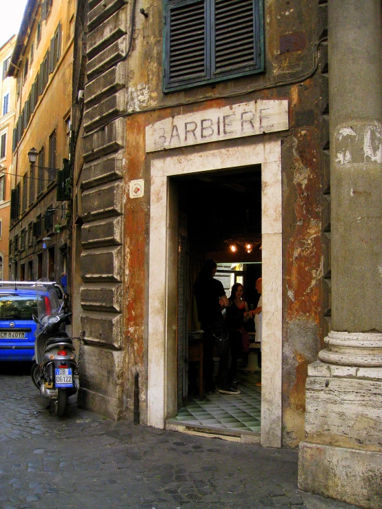 people walking by a car parked outside of an old building