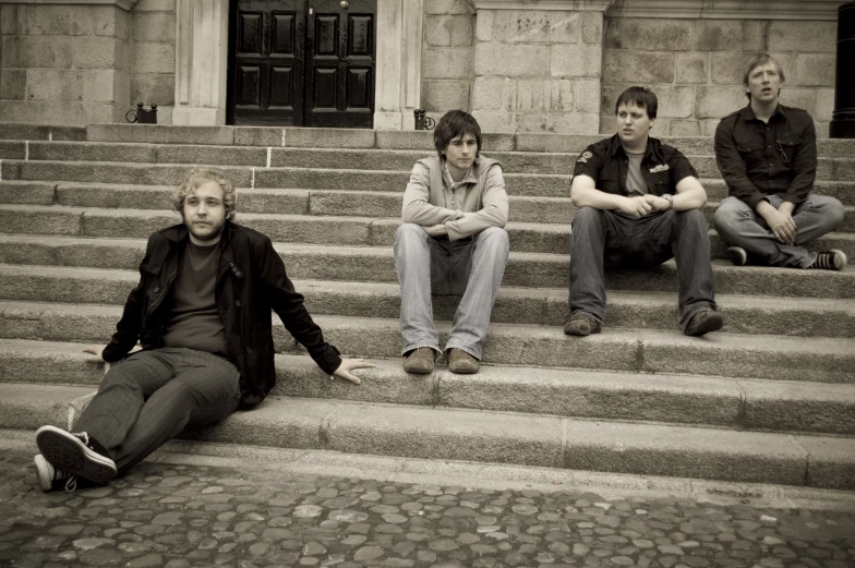 four guys are sitting on some steps outside