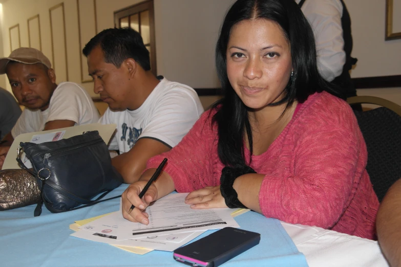 a woman sitting at a table signing an item