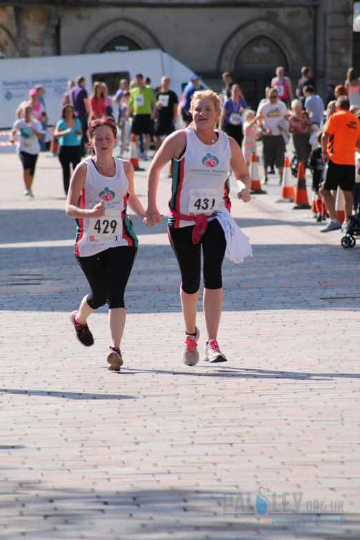 two young women run down a path in a competition