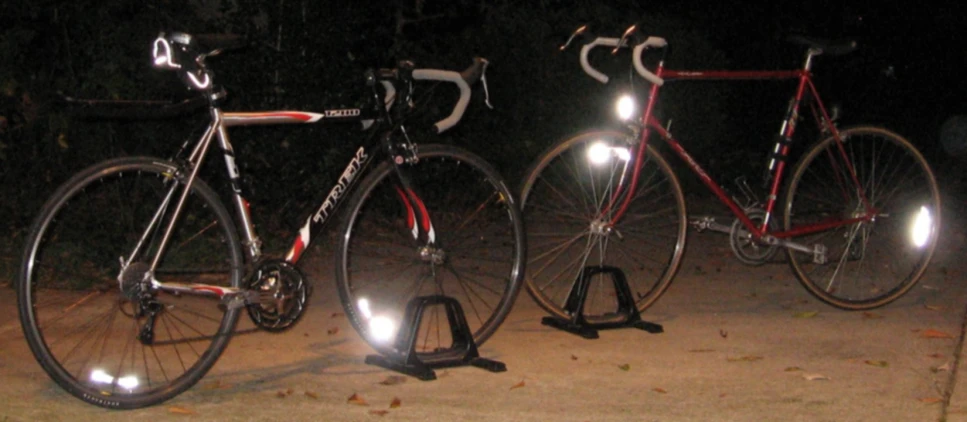 three bicycles are parked outside at night in the dark