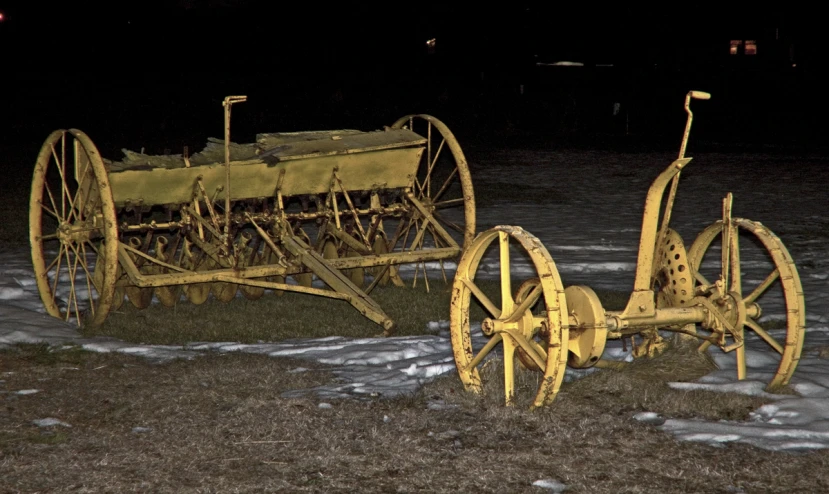 there are two old, rusty farm implements in the yard