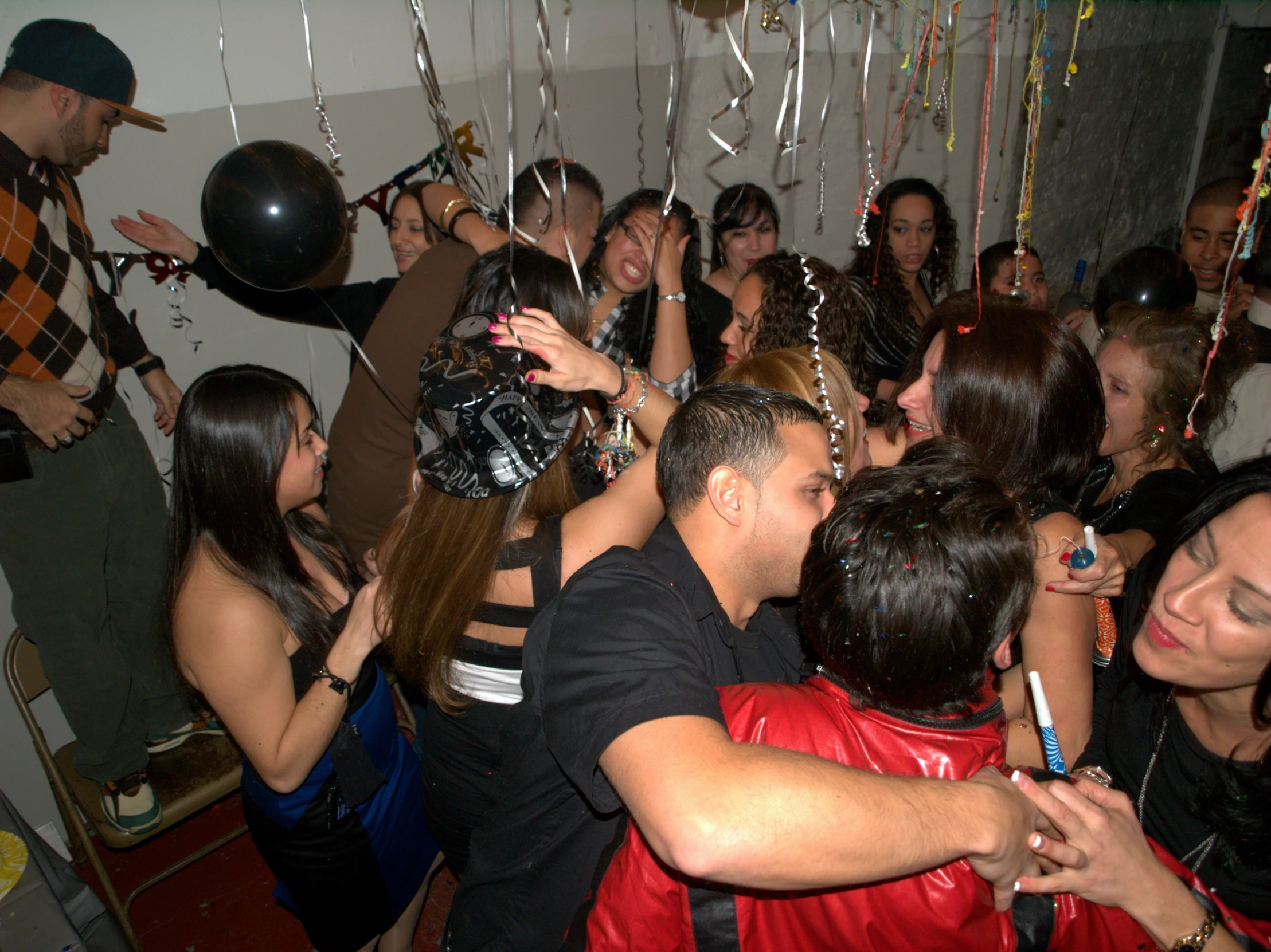 a group of people dancing together with balloons and streamers all around