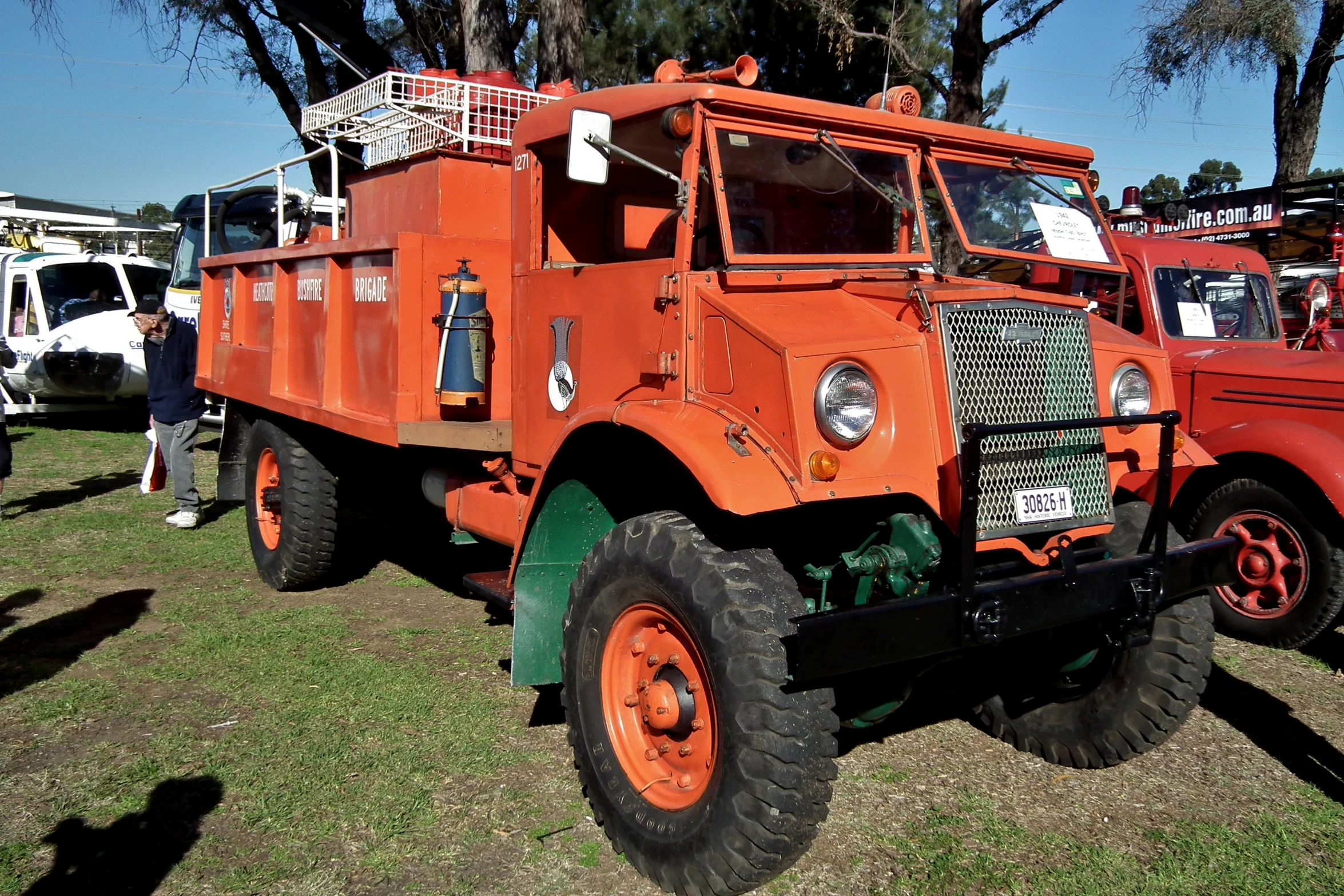 an old fashioned utility truck parked on grass with other trucks around