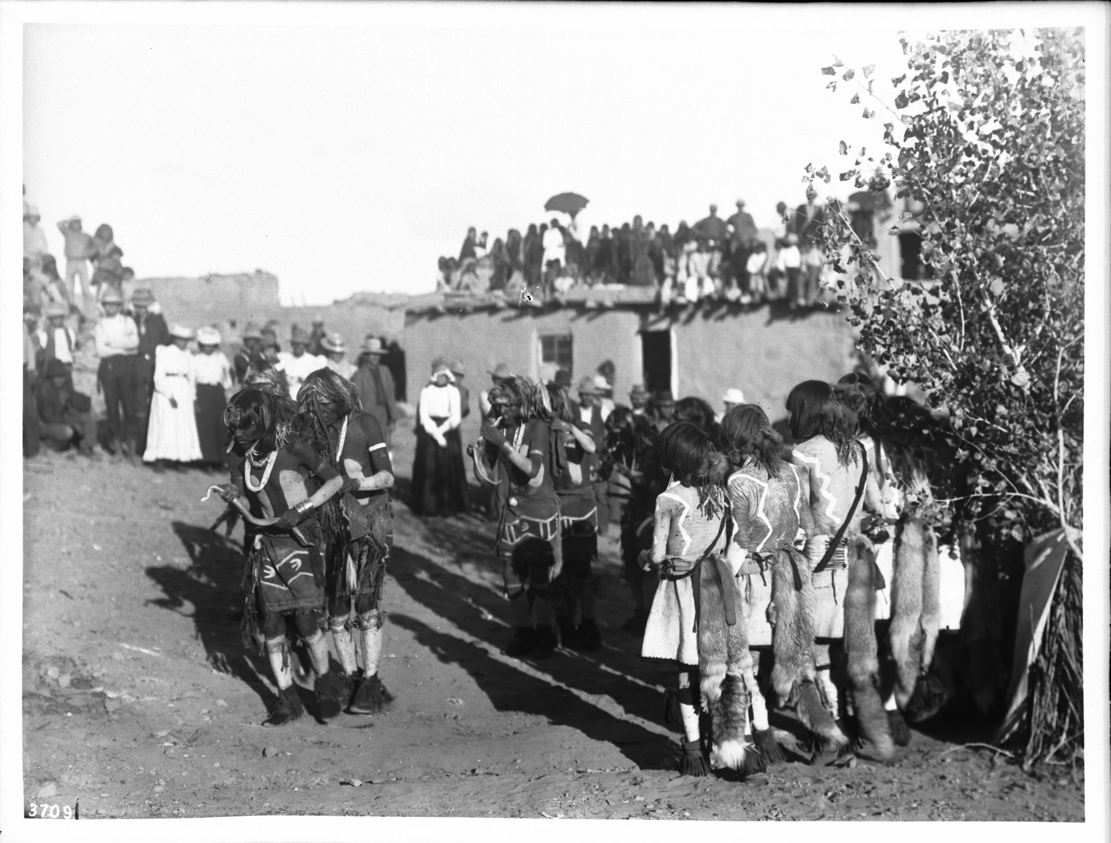 people walking around in the dirt with horse drawn wagons