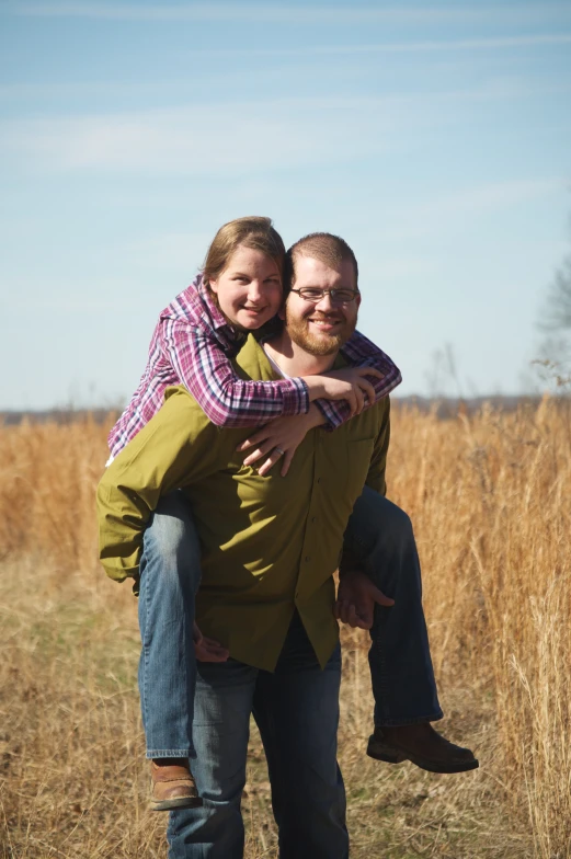 two people standing in the tall grass holding each other