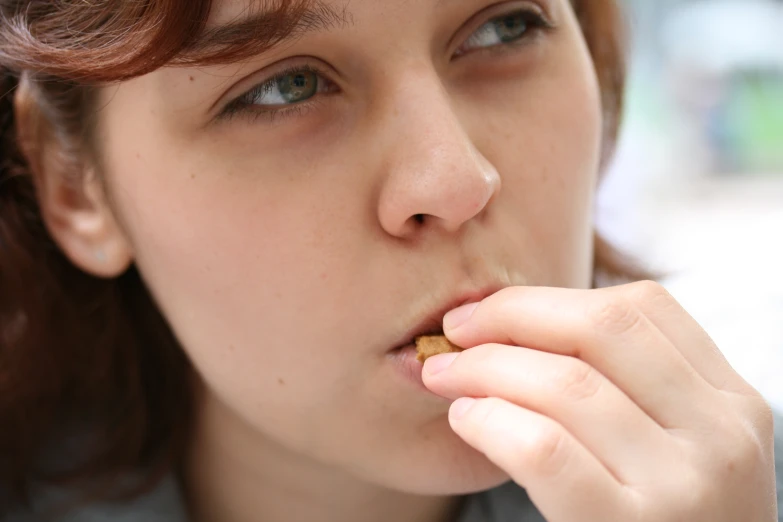 a woman in a grey shirt putting food in her mouth