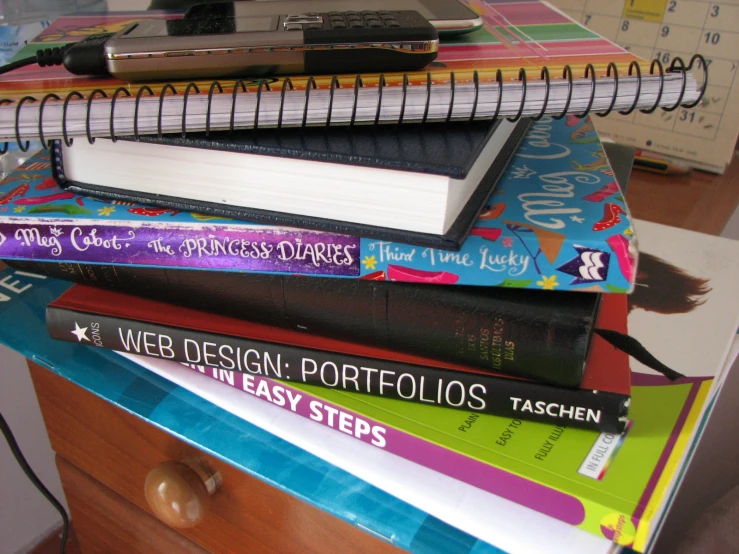 a pile of books on top of a desk next to another stack